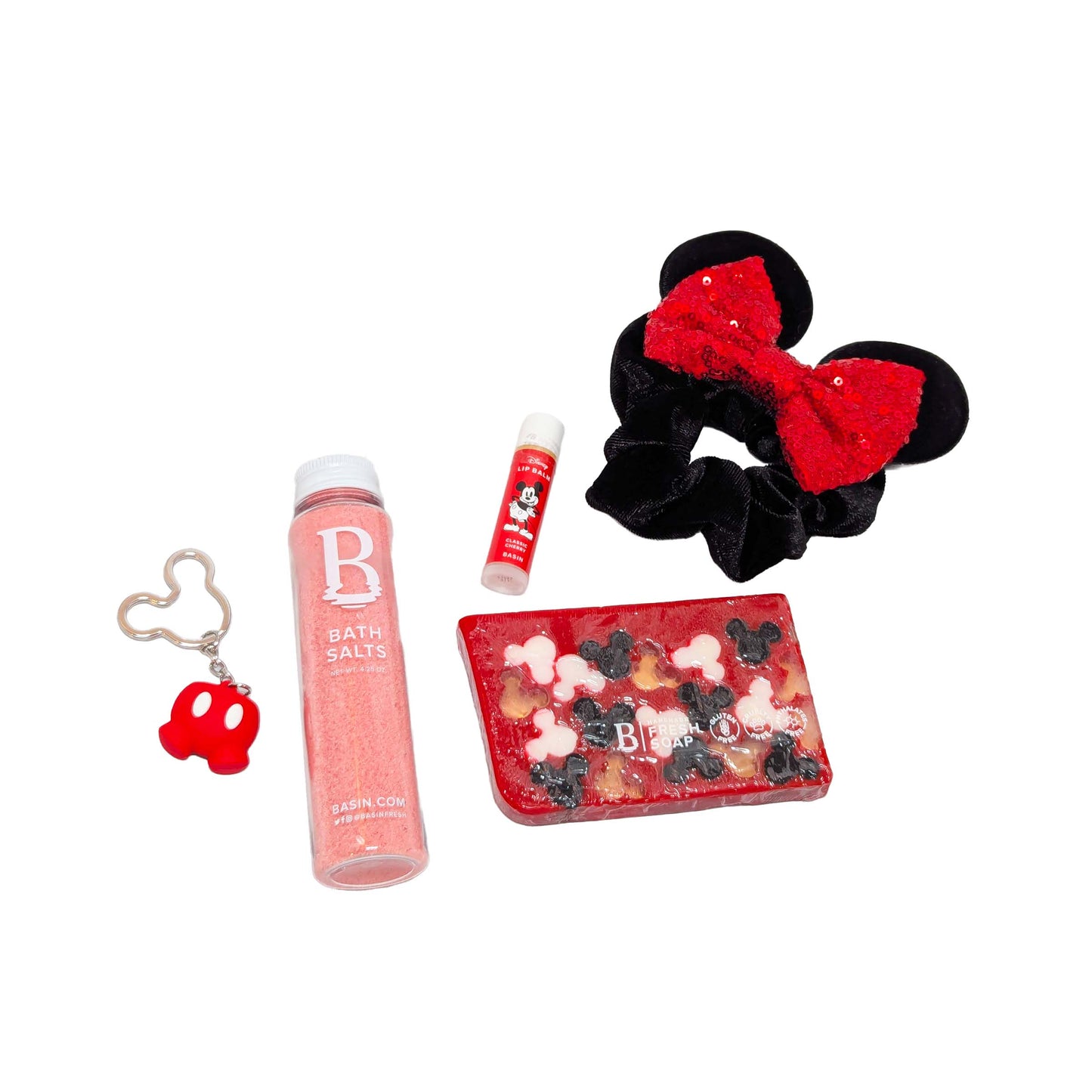 Licensed Basin Disney spa essentials deluxe set featuring a pink bath salts bottle, Mickey Mouse cherry lip balm, red Mickey silhouette bar soap, Minnie Mouse inspired scrunchie hair tie, and a Mickey pants keychain for custom Orlando resort gift boxes