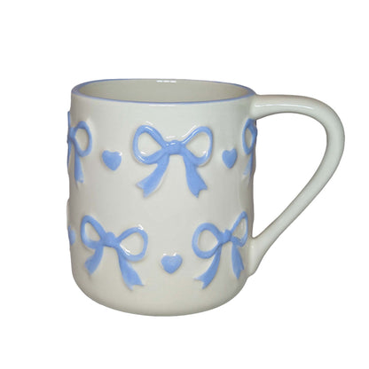 White ceramic mug with blue bow and heart patterns, perfect for themed Orlando resort gift baskets