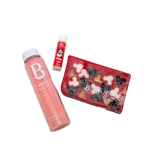 Licensed Basin Disney spa essentials standard set featuring a pink bath salts bottle, Mickey Mouse classic cherry lip balm, and red Mickey silhouette bar soap for custom Orlando resort gift boxes