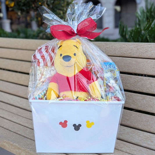 Custom Disney Winnie the Pooh gift basket filled with a licensed plush toy, assorted snacks, and bottled beverages for Orlando resort delivery
