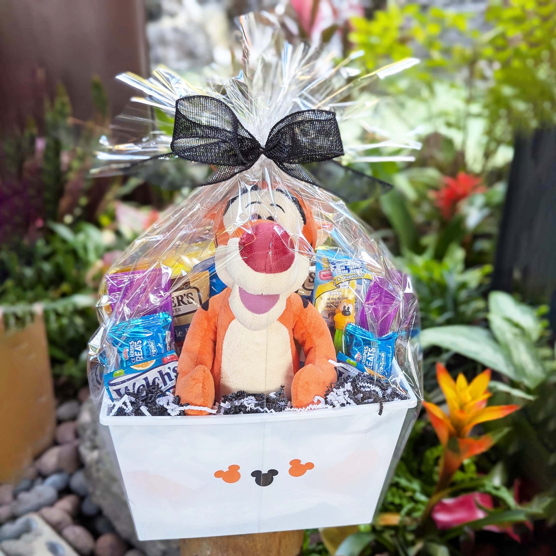 Custom Winnie the Pooh Tigger plush toy gift basket filled with sweet and salty snacks, bottled beverages, and a collectible PEZ dispenser for Orlando resort delivery