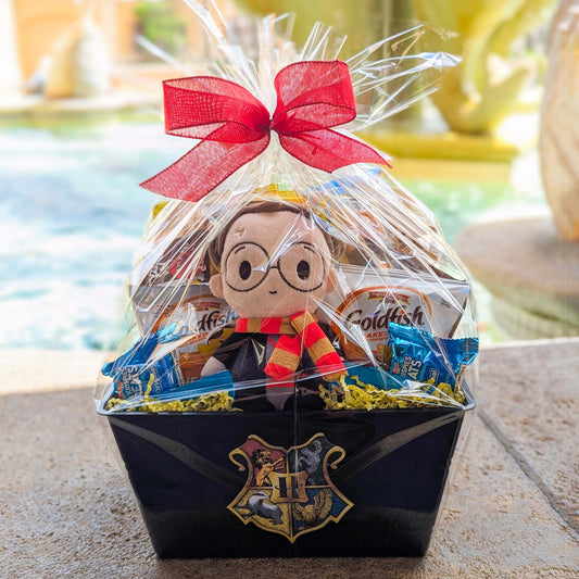 Harry Potter themed gift basket featuring a licensed bean bag plush toy and assorted snacks wrapped in clear cellophane with a red bow for Universal Orlando resort delivery