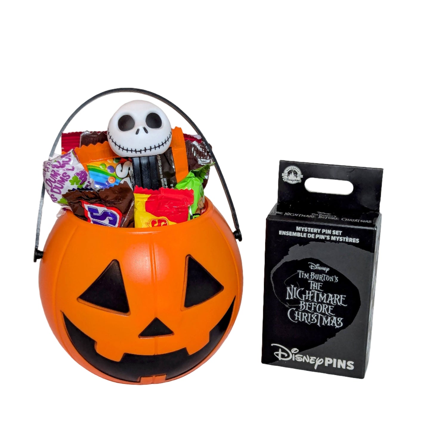 Mini Halloween Jack-o'-Lantern bucket filled with sweet treats and a Jack Skellington PEZ dispenser next to a Disney Nightmare Before Christmas mystery pin box